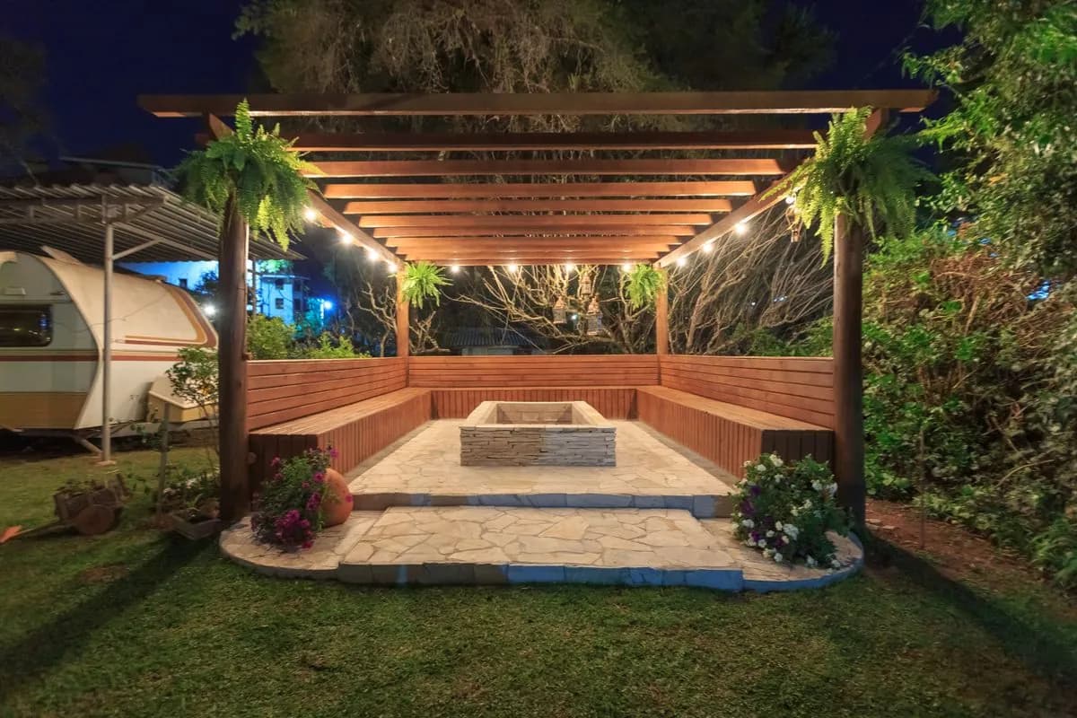 Timber pergola glowing with warm LED lighting over an outdoor seating area at night