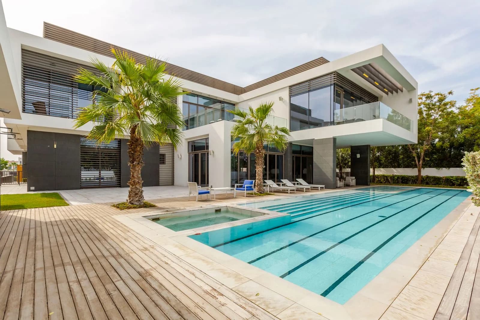 Modern villa in Dubai with a turquoise swimming pool framed by palm trees and lush landscaping