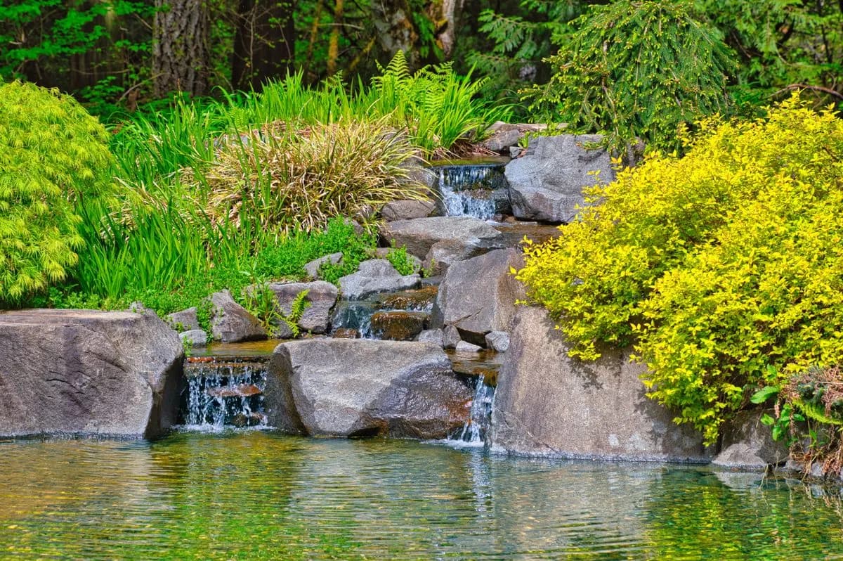Hand-set Hafeet stone waterfall with three catch pools in an Al Ain villa garden