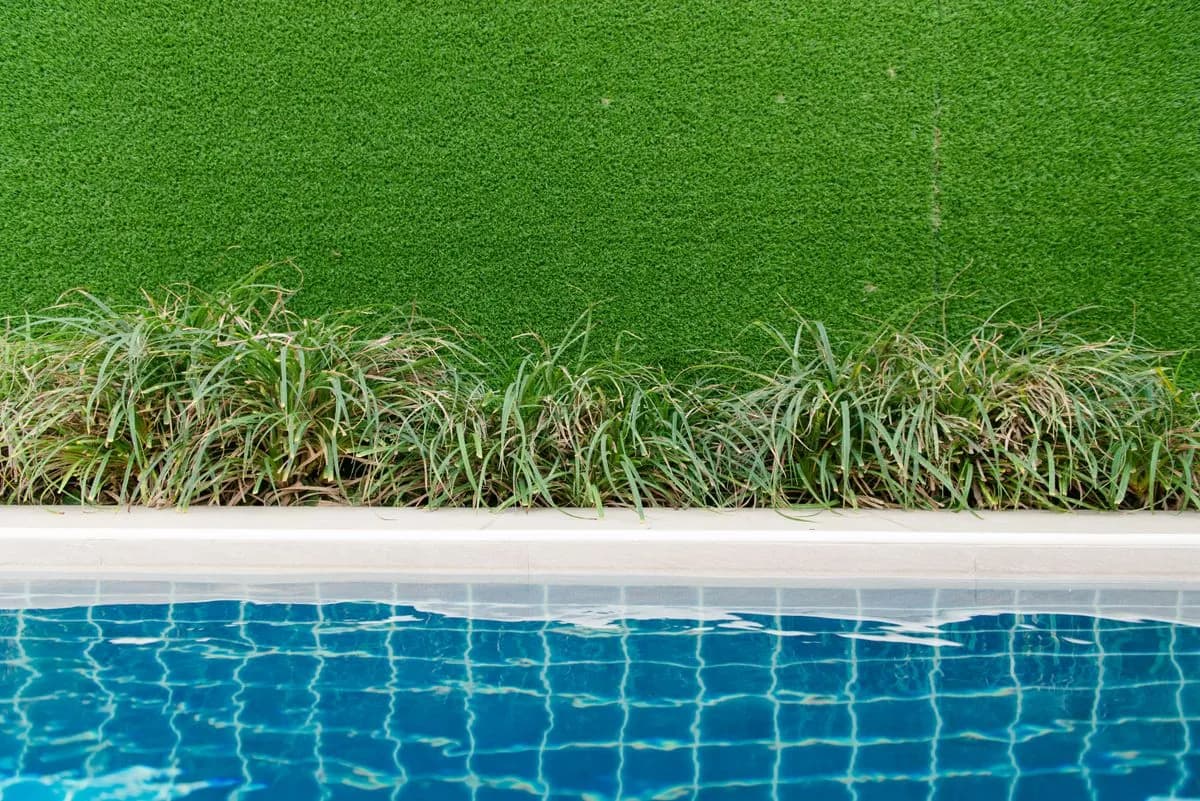 Child-safe artificial grass edging a villa swimming pool in Sharjah